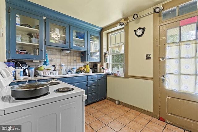 kitchen with blue cabinets, light tile patterned floors, decorative backsplash, and white electric range oven