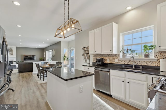 kitchen with a kitchen island, pendant lighting, white cabinetry, sink, and stainless steel appliances