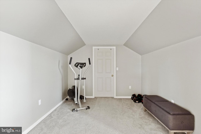 workout area featuring vaulted ceiling and light colored carpet