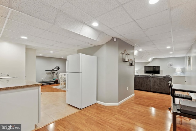 kitchen with white refrigerator, white cabinetry, a paneled ceiling, and light wood-type flooring