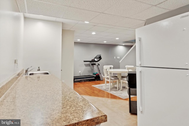 kitchen featuring white refrigerator, sink, and a drop ceiling