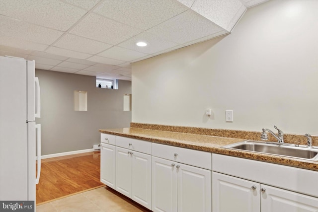 kitchen featuring white cabinetry, a paneled ceiling, sink, and white fridge