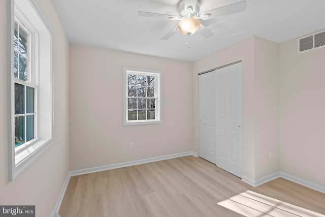 unfurnished bedroom with ceiling fan, light wood-type flooring, and a closet