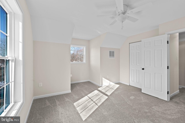 unfurnished bedroom featuring ceiling fan, a closet, vaulted ceiling, and light carpet