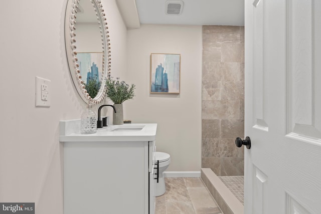 bathroom with vanity, a tile shower, and toilet