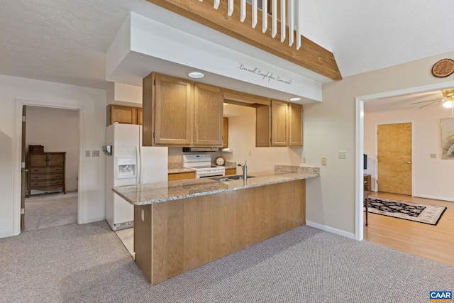 kitchen featuring sink, light colored carpet, light stone counters, kitchen peninsula, and white appliances