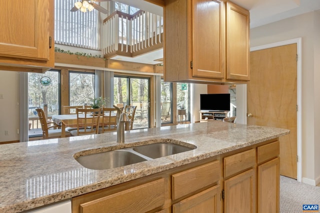 kitchen with sink, light stone countertops, ceiling fan, and light brown cabinets