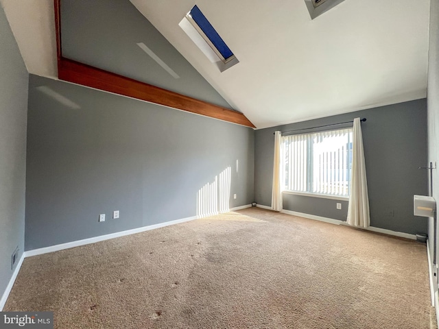 spare room featuring carpet and vaulted ceiling with skylight