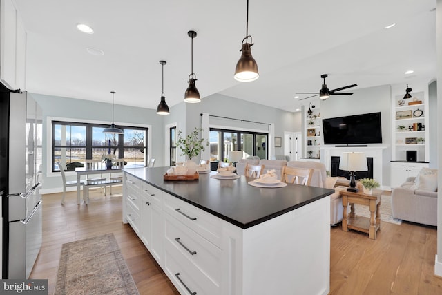 kitchen featuring a center island, light hardwood / wood-style floors, hanging light fixtures, and white cabinets