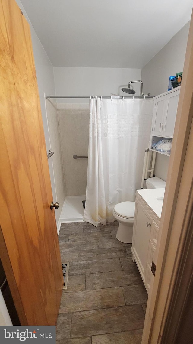 bathroom with vanity, curtained shower, and toilet