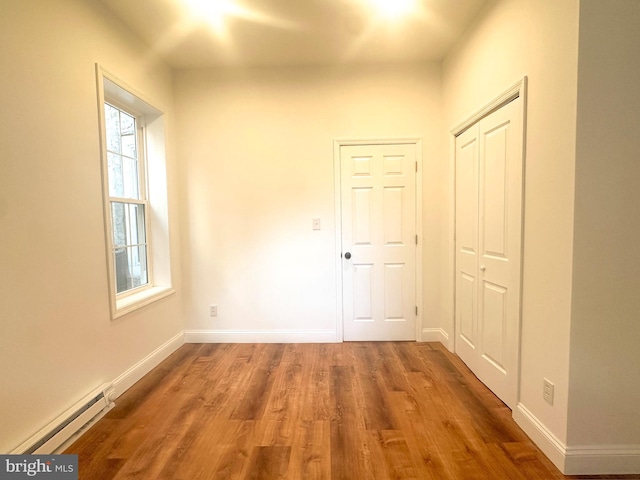 corridor with hardwood / wood-style flooring and baseboard heating