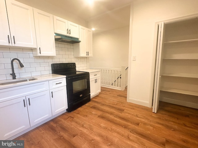 kitchen featuring hardwood / wood-style flooring, black range with electric stovetop, sink, and white cabinets