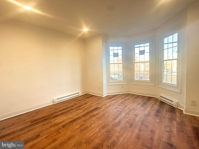 unfurnished room featuring baseboard heating and dark hardwood / wood-style flooring