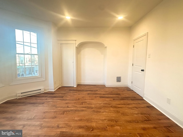 unfurnished room with a baseboard radiator and dark wood-type flooring