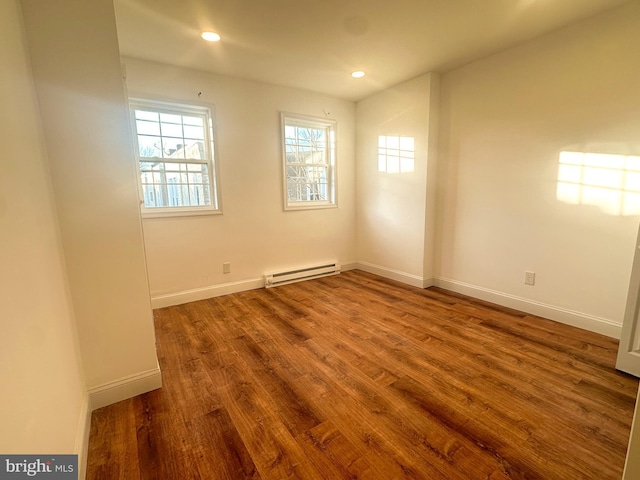 unfurnished room with hardwood / wood-style floors and baseboard heating