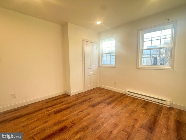 empty room featuring hardwood / wood-style floors and baseboard heating