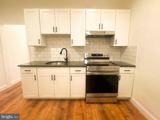 kitchen with sink, stainless steel range with electric cooktop, wood-type flooring, dark stone countertops, and white cabinets