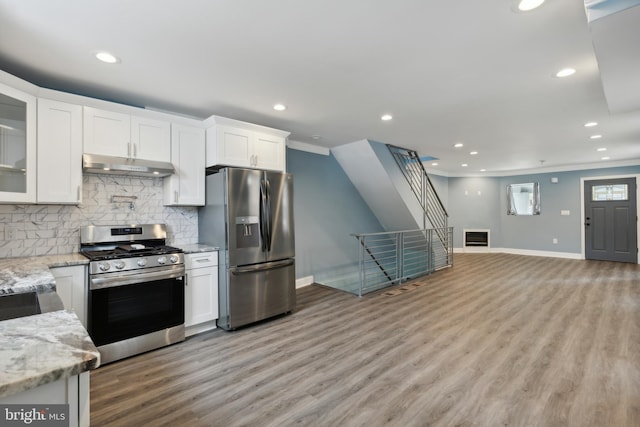 kitchen with light stone countertops, backsplash, stainless steel appliances, and white cabinets