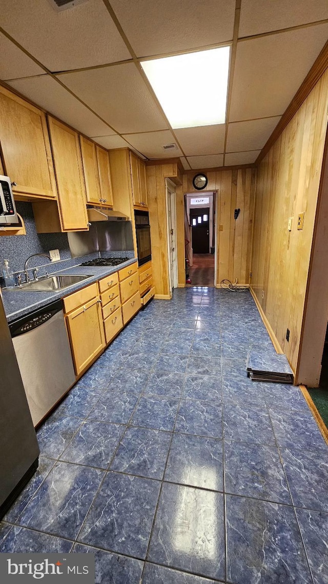 kitchen featuring a paneled ceiling, black oven, wood walls, dishwasher, and sink