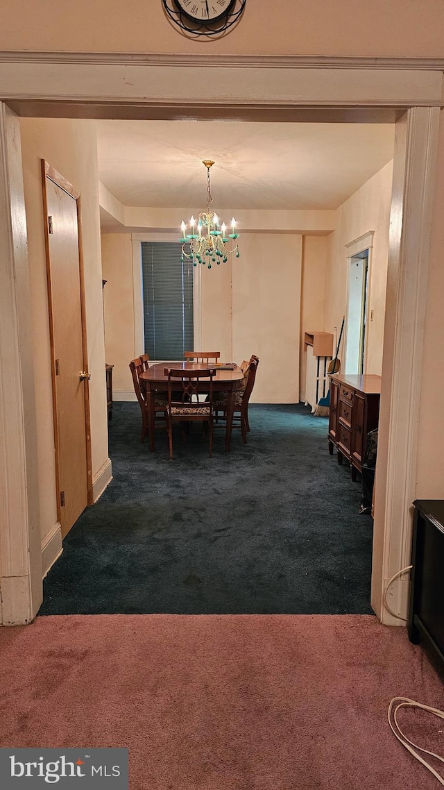 dining space featuring dark carpet and a notable chandelier