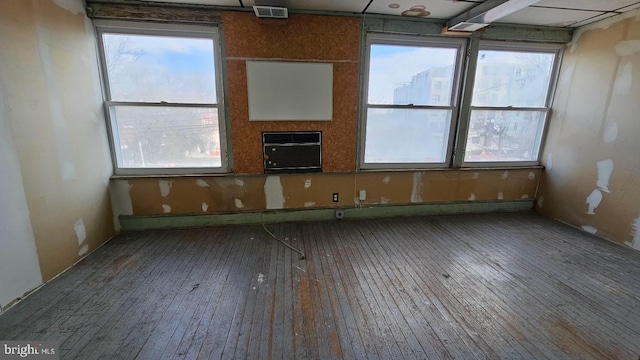 unfurnished room featuring wood-type flooring, an AC wall unit, and a wealth of natural light