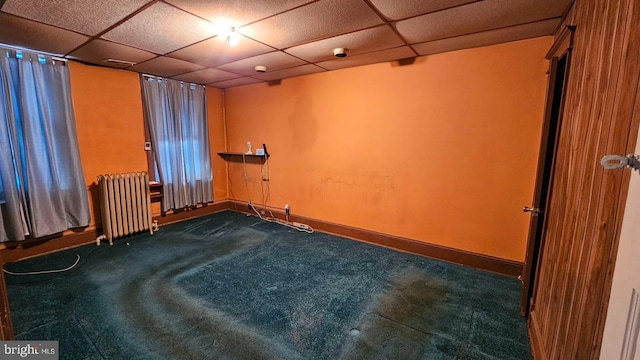 spare room with carpet flooring, radiator, and a drop ceiling