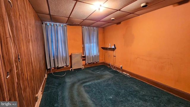 carpeted spare room with a drop ceiling and radiator