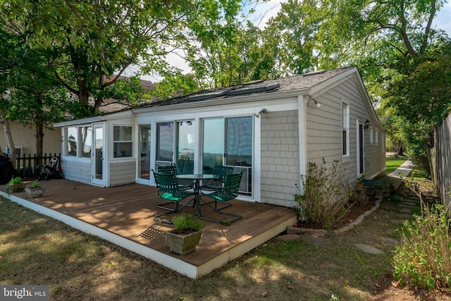 view of outbuilding featuring fence and a sunroom