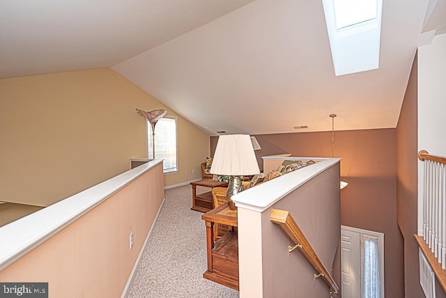 hallway featuring light colored carpet and vaulted ceiling with skylight