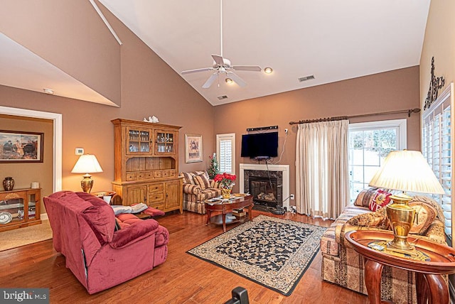 living room featuring a premium fireplace, high vaulted ceiling, dark hardwood / wood-style floors, and ceiling fan