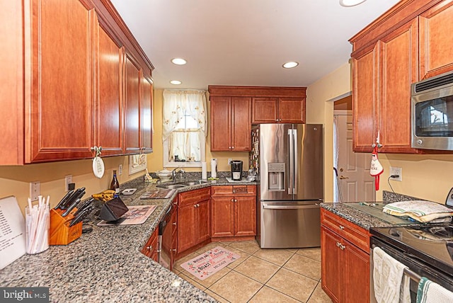 kitchen with dark stone countertops, appliances with stainless steel finishes, sink, and light tile patterned floors