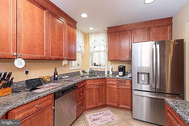 kitchen featuring appliances with stainless steel finishes, sink, light tile patterned floors, and dark stone counters