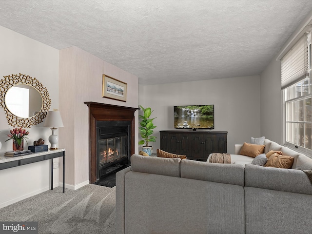 carpeted living room featuring a fireplace with flush hearth, a textured ceiling, and baseboards