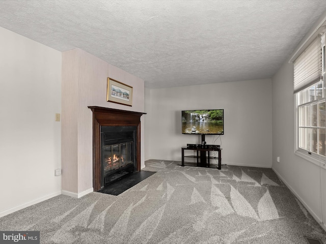 unfurnished living room featuring carpet, a fireplace with flush hearth, visible vents, and baseboards