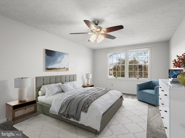 carpeted bedroom featuring ceiling fan, a textured ceiling, and baseboards