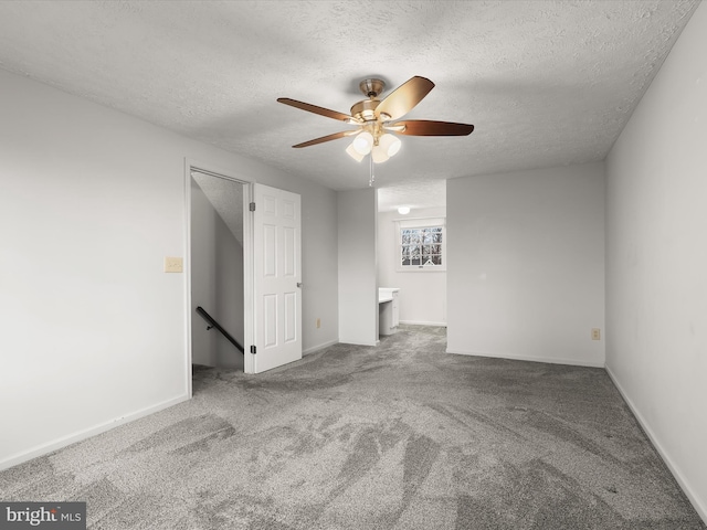 empty room with a textured ceiling, carpet floors, and baseboards