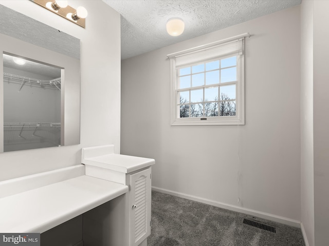 bathroom with baseboards, visible vents, a textured ceiling, and vanity