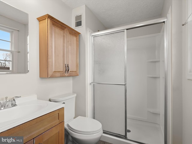 full bath featuring visible vents, toilet, a stall shower, a textured ceiling, and vanity