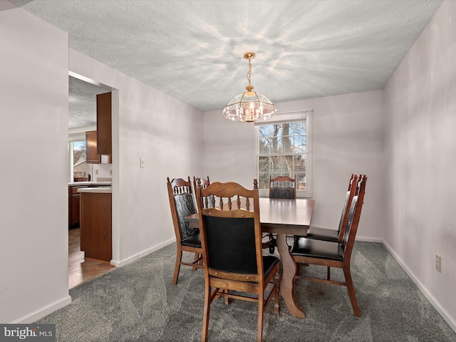 dining room with a textured ceiling, dark carpet, and baseboards