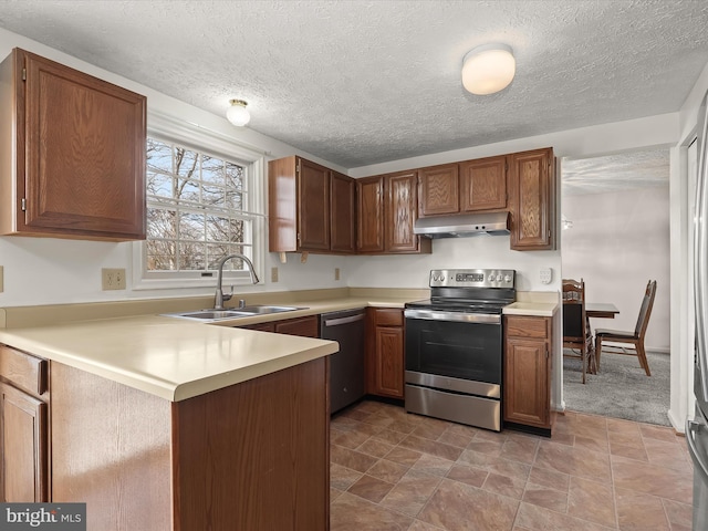 kitchen with light countertops, appliances with stainless steel finishes, a sink, a peninsula, and under cabinet range hood