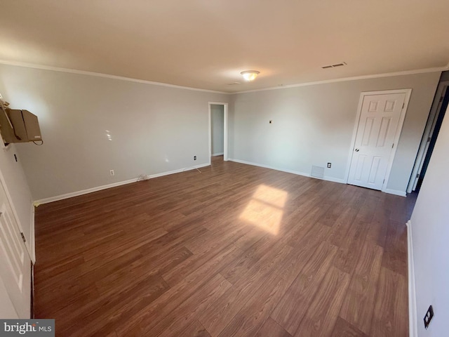 empty room featuring dark wood-type flooring and crown molding