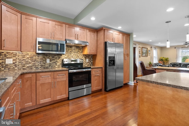 kitchen with stainless steel appliances, hanging light fixtures, dark hardwood / wood-style flooring, and decorative backsplash