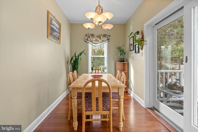 dining area with hardwood / wood-style floors and a notable chandelier