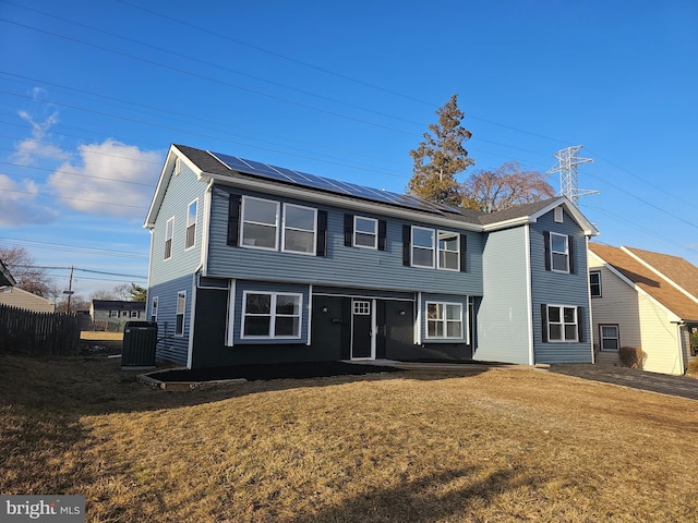 front of property featuring central AC, a front yard, and solar panels