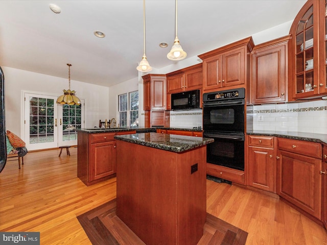 kitchen with hanging light fixtures, tasteful backsplash, a center island, and black appliances