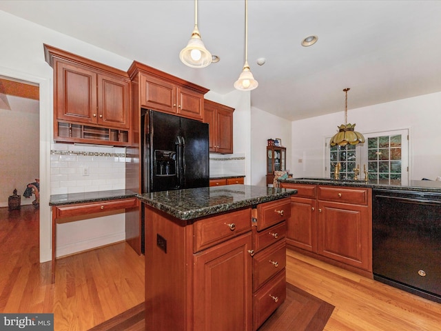 kitchen featuring hanging light fixtures, dark stone countertops, a kitchen island, light hardwood / wood-style floors, and black appliances