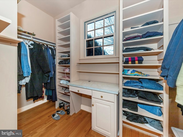 spacious closet featuring built in desk and light hardwood / wood-style flooring