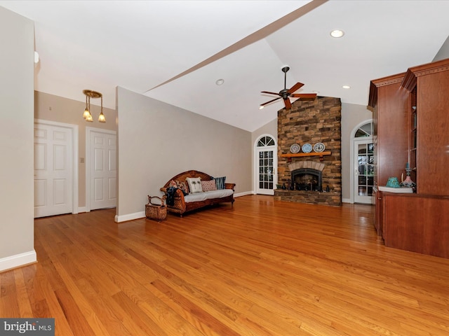 unfurnished living room featuring ceiling fan, a stone fireplace, high vaulted ceiling, and light hardwood / wood-style flooring