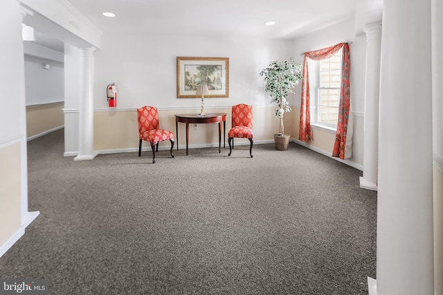 living area featuring decorative columns and dark colored carpet