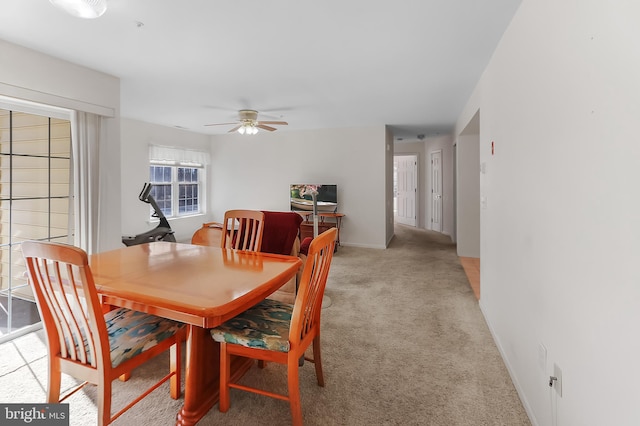 dining area with ceiling fan and light carpet